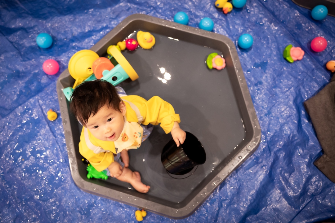 Child in water play tray with toys