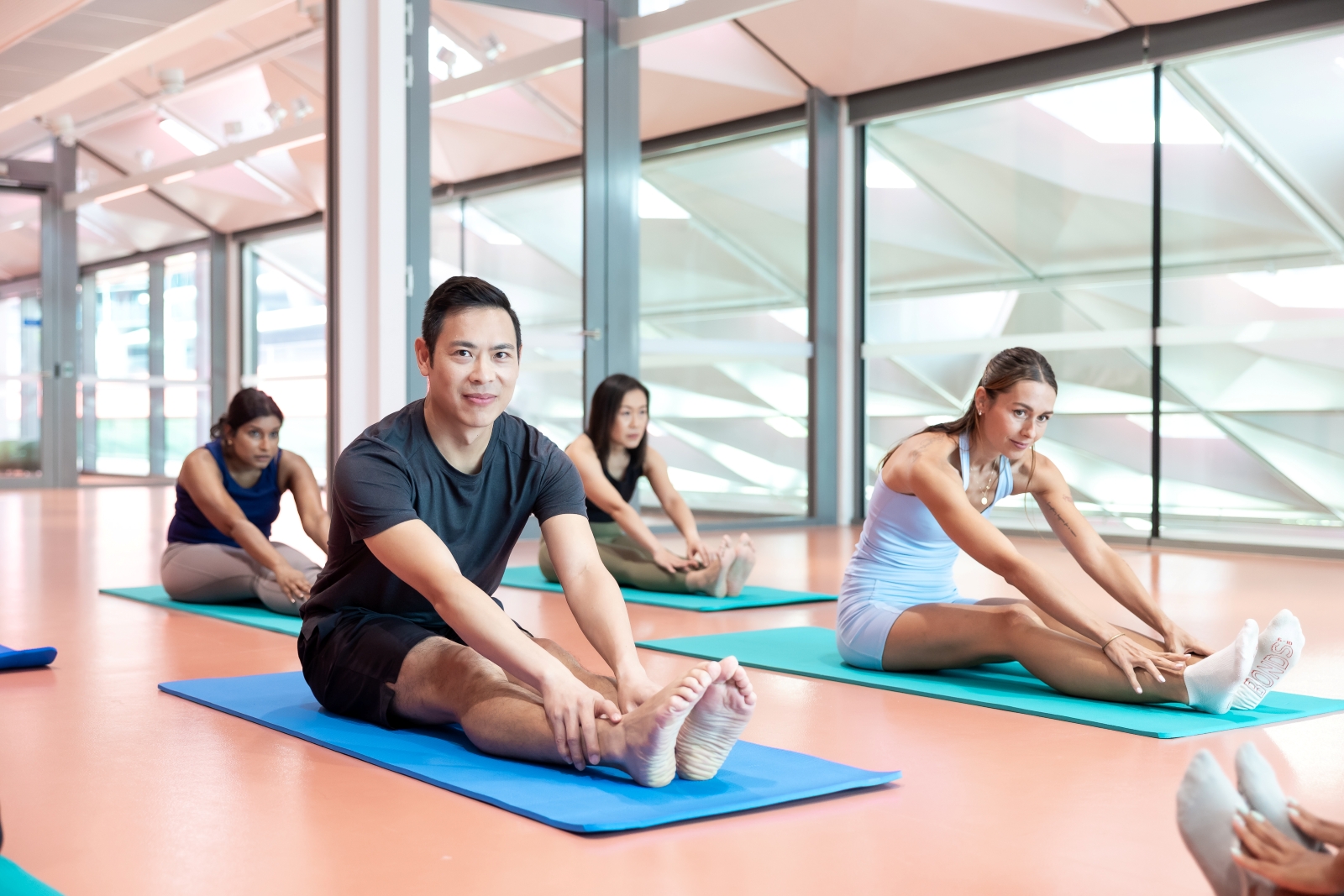 Group of men and women sitting on yoga mats stretching